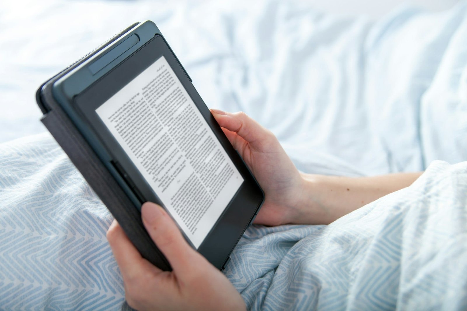 Girl reading ebook on tablet reader in bed at home