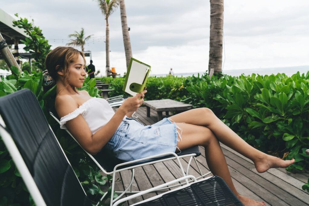 Woman reading ebook on patio near sea